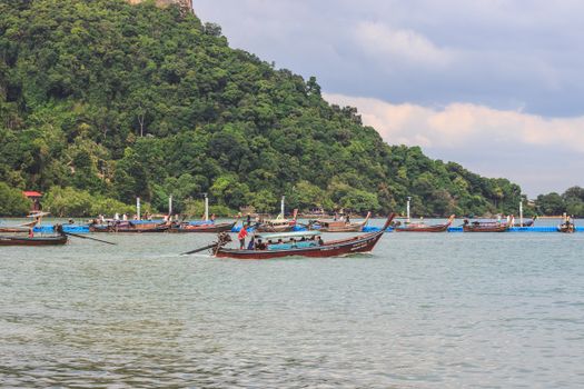A scenic view of traditional boats floating on clear waters near a lush green hill, ideal for tourism.