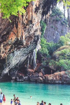 Lush tropical beach with towering limestone cliffs and clear turquoise water, perfect for summer vacations.