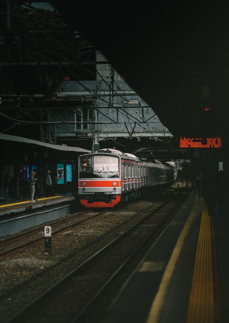 A commuter train arriving at a busy railway station in Jakarta, Indonesia.