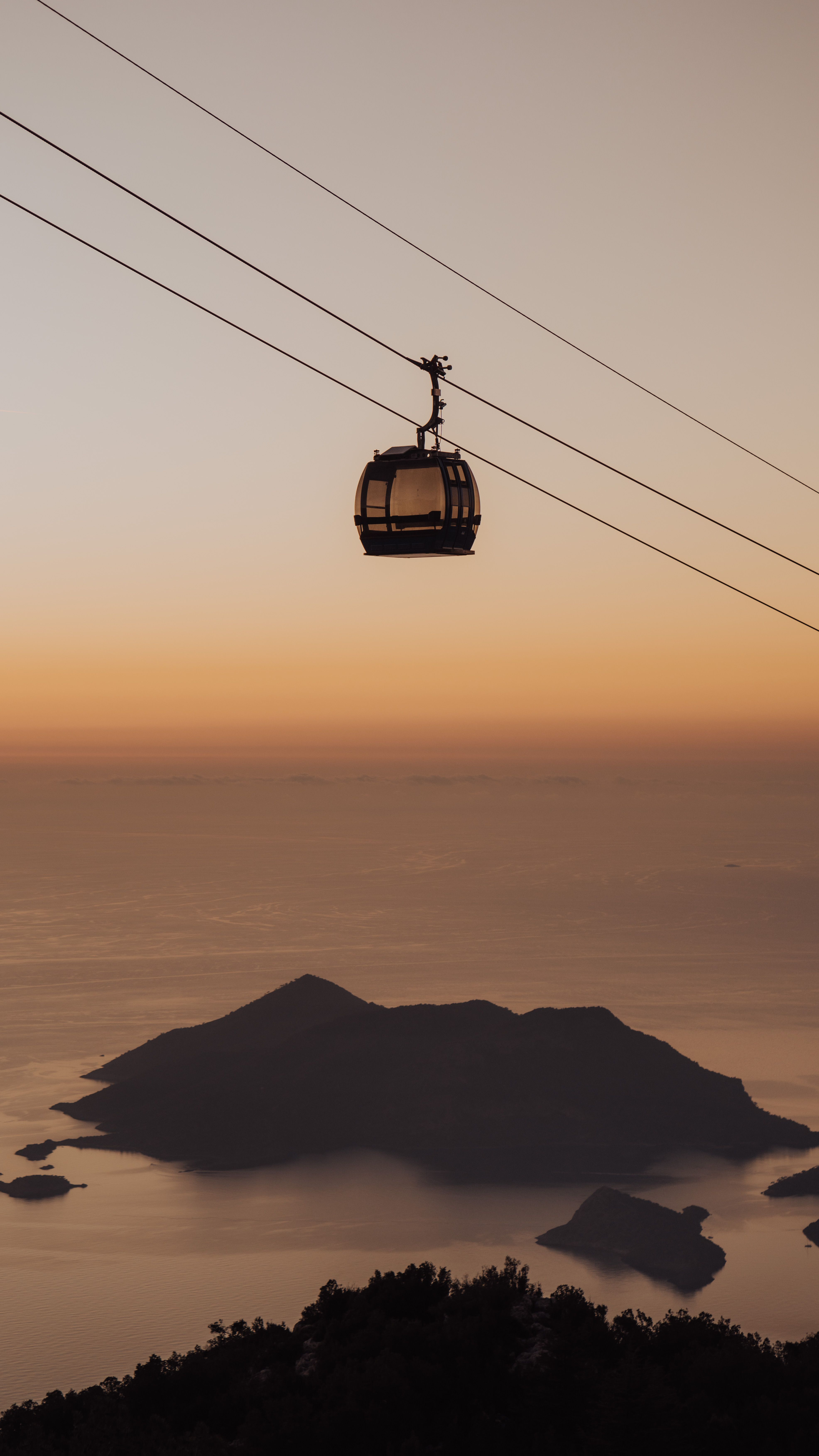 Silhouette of a cable car against a vibrant sunset over the Antalya coastline, capturing the serene landscape.