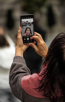 A woman capturing a selfie on a smartphone in an outdoor urban setting.