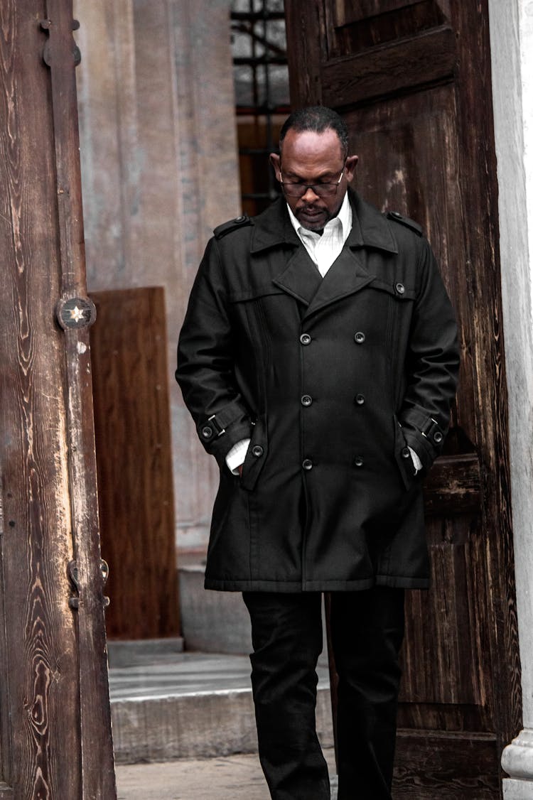 Man In A Black Coat Walking Out The Door 