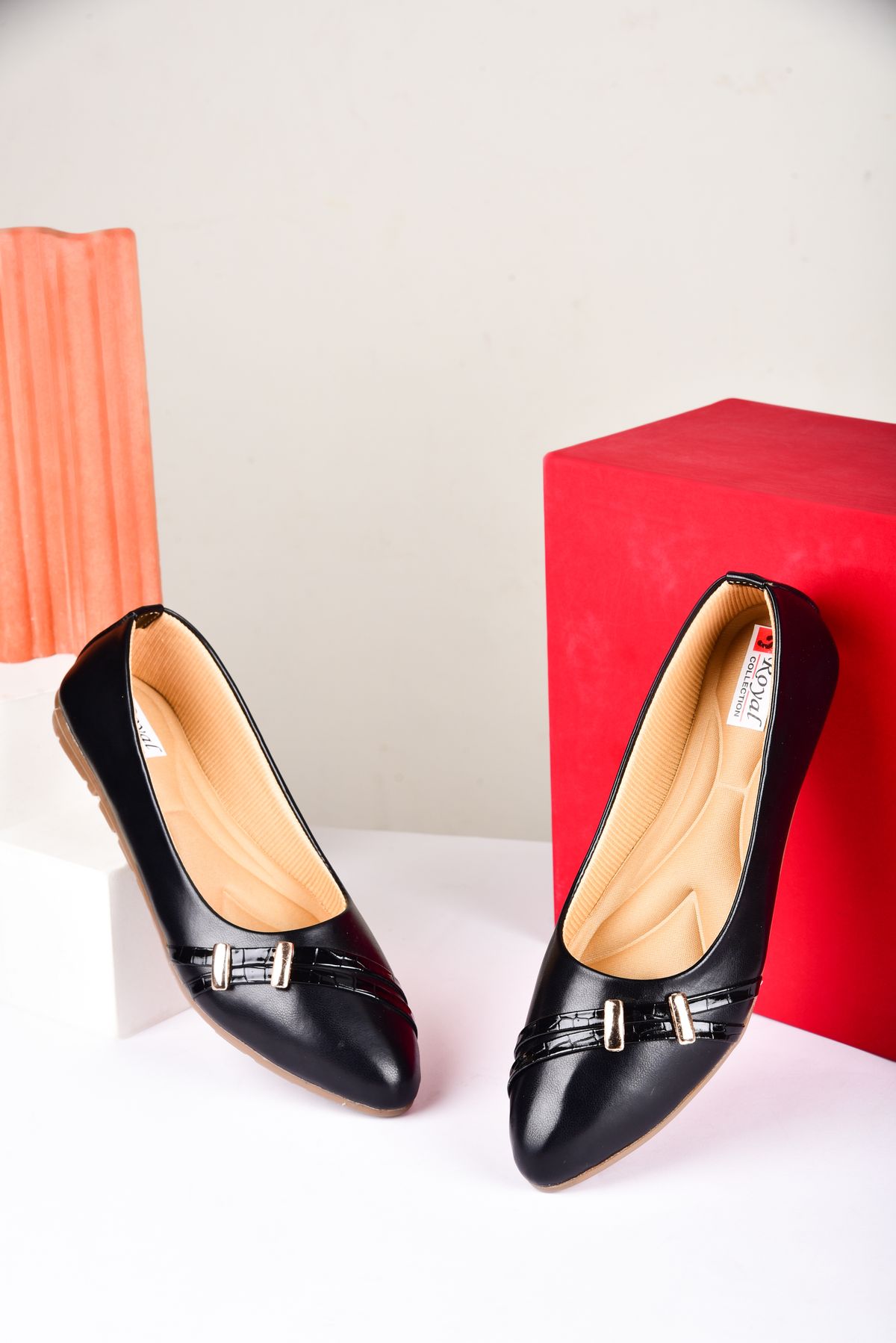 Black ballet flat with criss-cross straps displayed in a studio setting