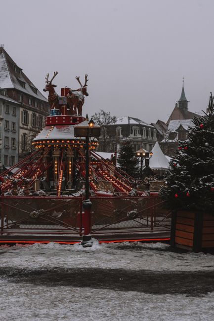 Charming Christmas carousel in snowy old town setting, capturing festive winter spirit.