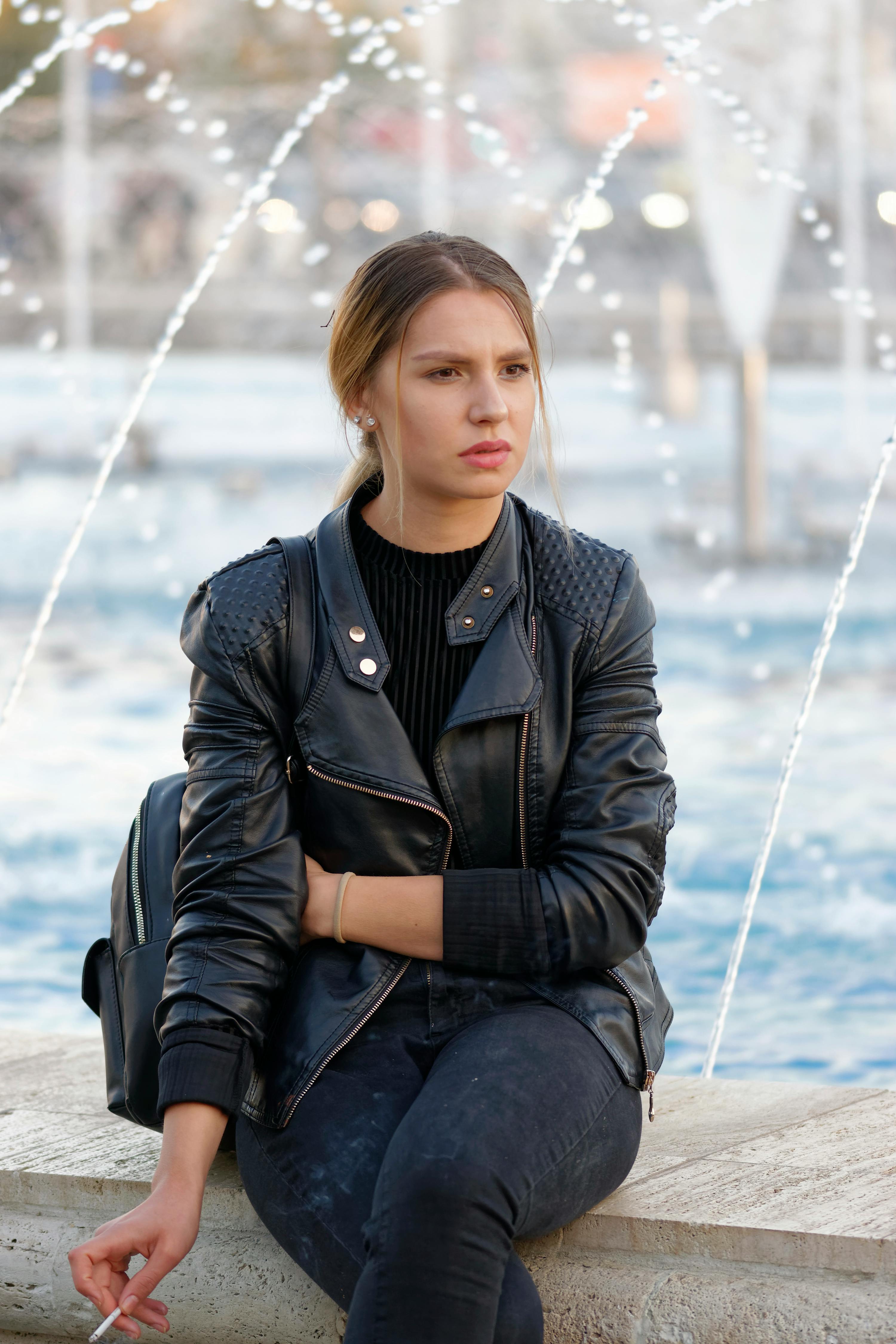 Woman sitting beside a fountain | Photo: Pexels