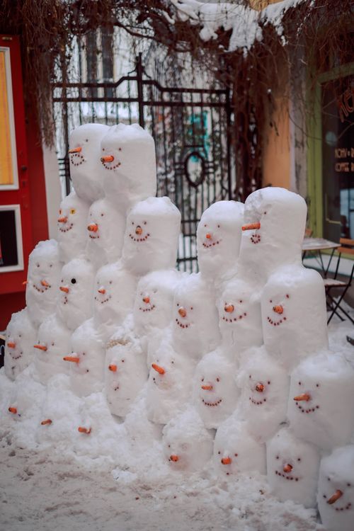 Free A group of adorable snowmen lined up in a snowy yard, creating a whimsical winter scene. Stock Photo