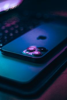 A sleek modern smartphone lying face down on a desk with ambient lighting highlighting its camera design.
