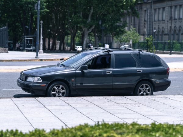 Black station wagon on a tree-lined street — photo by Mario Amé on Pexels