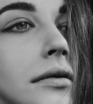 Striking black and white close-up portrait of a woman's face with smooth skin and straight hair.
