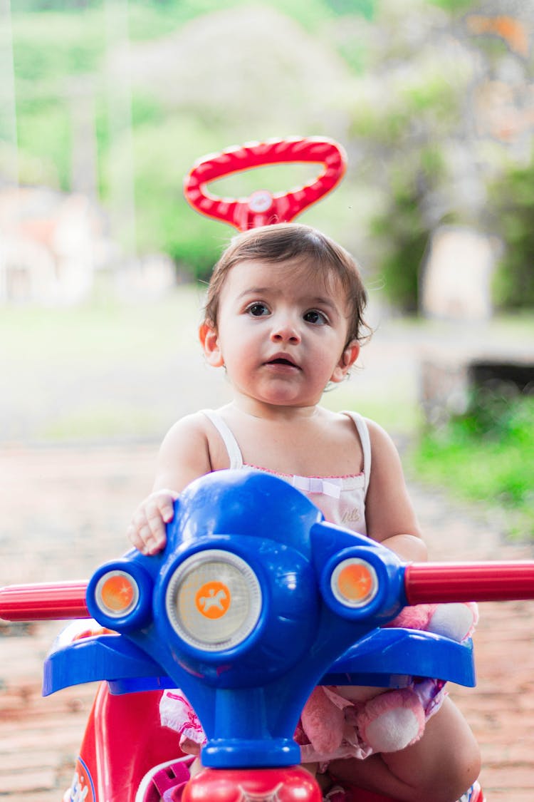 A Young Girl Riding On Her Toy Bike