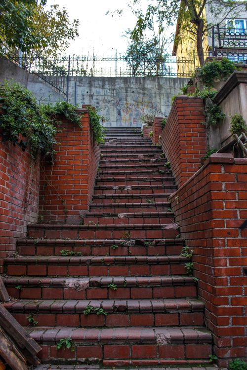 Free Vertical shot of a red brick stairway surrounded by greenery in İstanbul, Turkey. Stock Photo