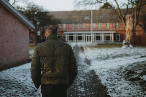 Back View of a Man Walking on a Pathway During Winter