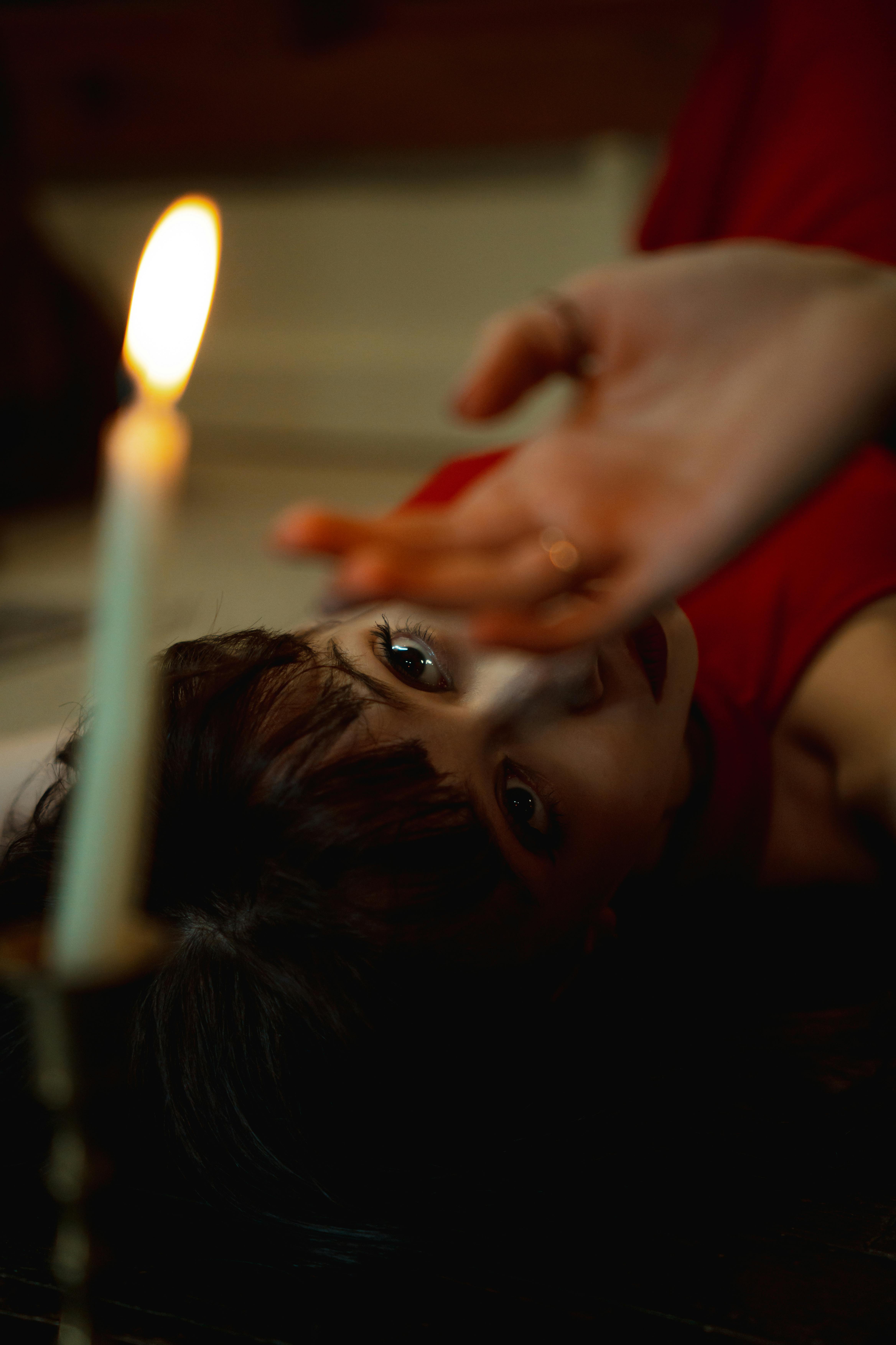 Woman in candlelit room, relaxed and surrendered, soft glow highlighting blissful expression