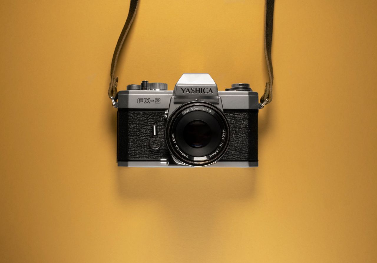 a classic yashica fx 2 film camera suspended against a vibrant yellow