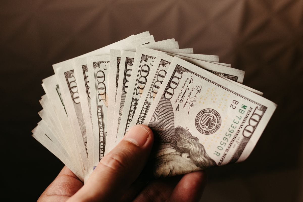Seseorang memegang beberapa lembar uang kertas 100 dolar Amerika Serikat