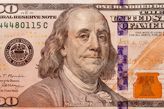 Detailed close-up of a one hundred dollar bill showcasing Benjamin Franklin, highlighting currency details.
