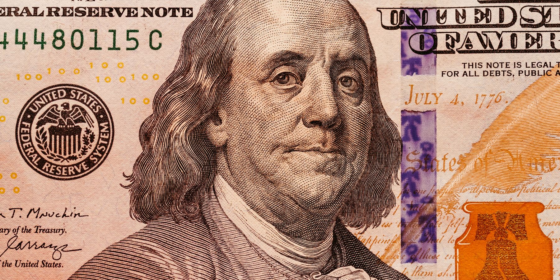 Detailed close-up of a one hundred dollar bill showcasing Benjamin Franklin, highlighting currency details.