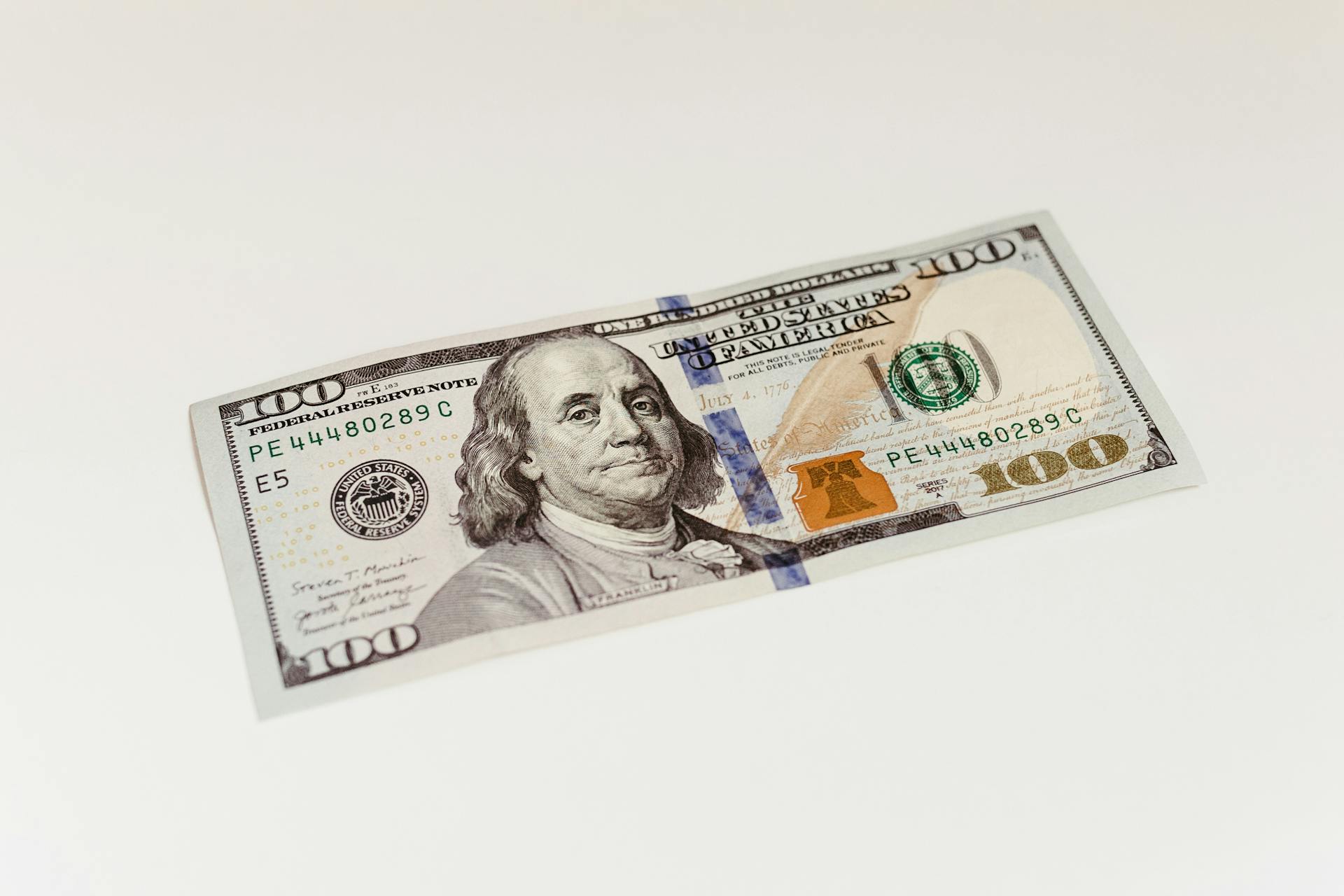 Detailed image of a US 100 dollar bill featuring Benjamin Franklin on a plain white surface.