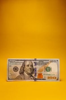 Close-up of a US dollar banknote on a bright yellow background, offering ample copy space.