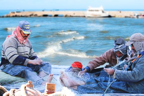 Free Local fishermen repair their nets by the sea in Al Max, Alexandria, Egypt. Stock Photo