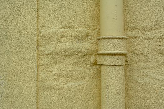 Textured yellow wall featuring a painted pipe for industrial or construction themes.