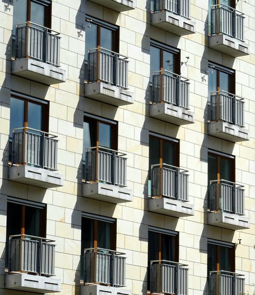 Free Detailed view of a modern apartment building with multiple balconies and reflective windows. Stock Photo