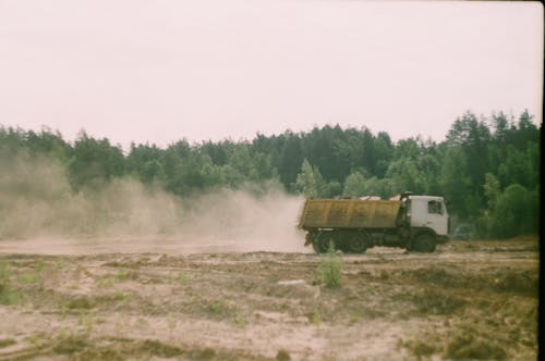 A Dump Truck on the Dirt Ground Near the Trees