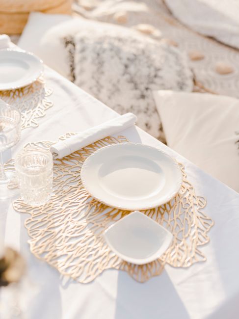 Stylish outdoor dining setup featuring white plates, glassware, and elegant decor.