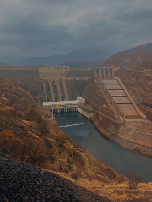 Free A dramatic landscape featuring a large hydroelectric dam nestled in a river valley with hills. Stock Photo