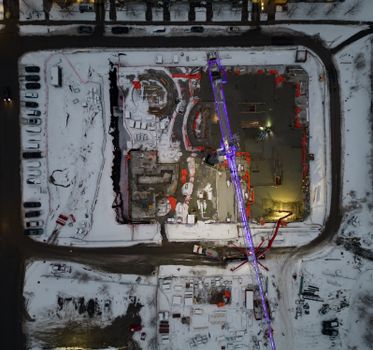 Aerial view of a construction site covered in snow, captured at night in Ottawa, Canada.