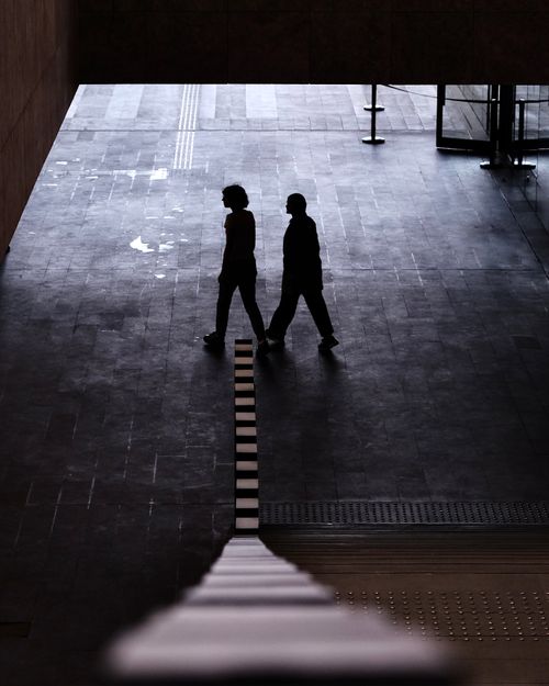 Free Moody silhouette shot of two people walking on an urban pathway, captured from above. Stock Photo