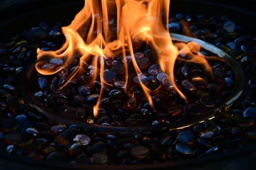 Close-up view of mesmerizing fire flames dancing over decorative glass stones in a fire pit.