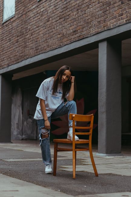 Young woman posing outdoors in casual fashion with jeans and t-shirt, creating a modern urban style.
