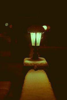 A streetlamp illuminated in a snowy winter night, casting a warm glow.