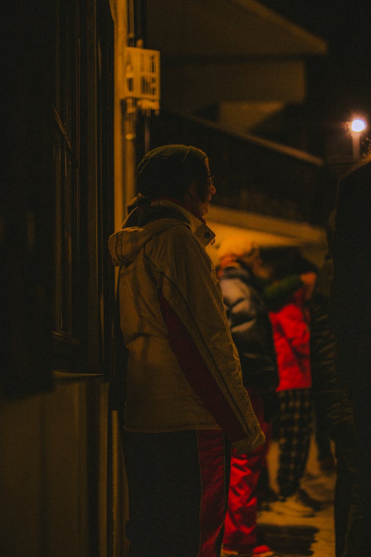 People Wearing Winter Clothes Standing Outside A House