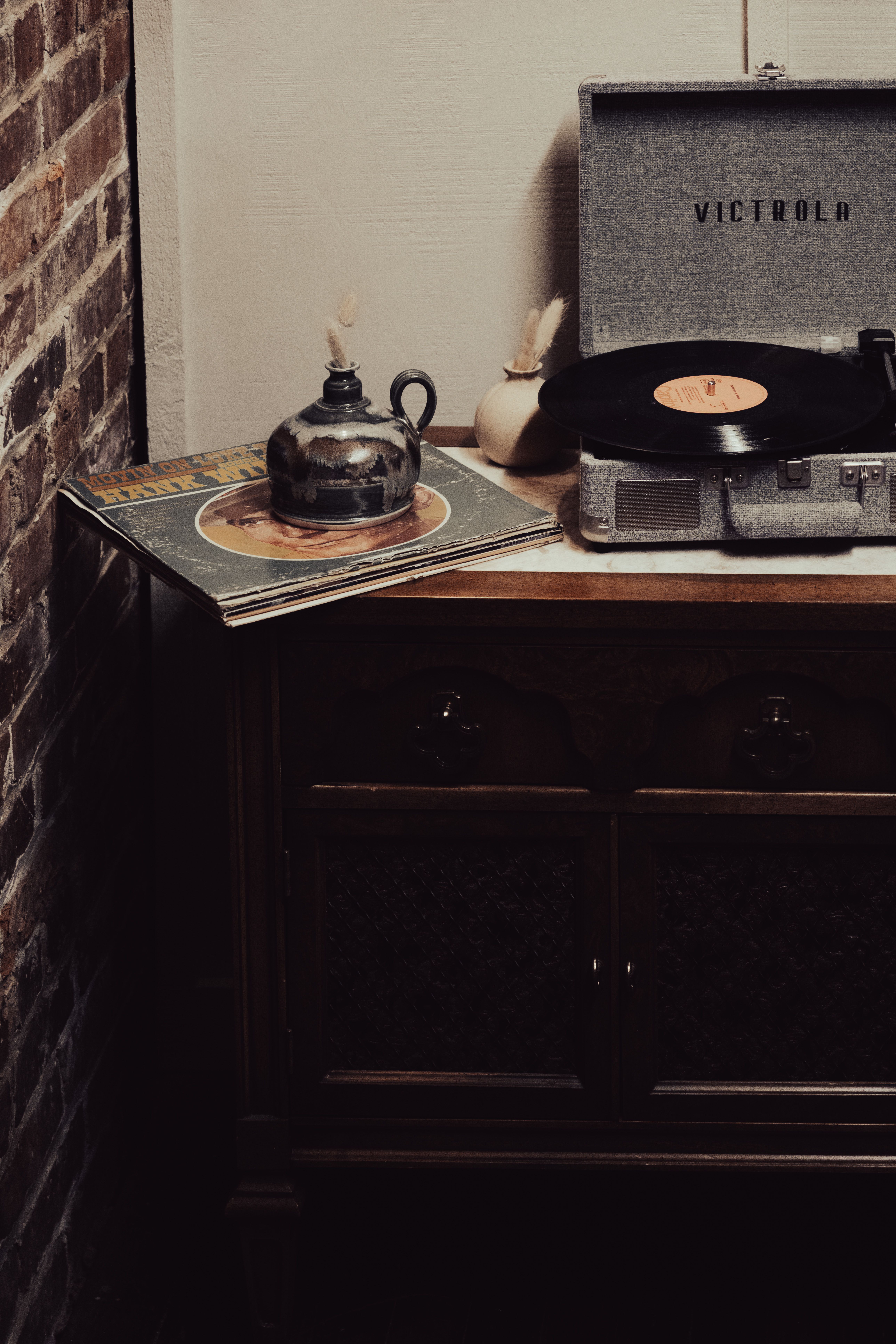 A vintage turntable setup with vinyl records on an antique wooden cabinet.