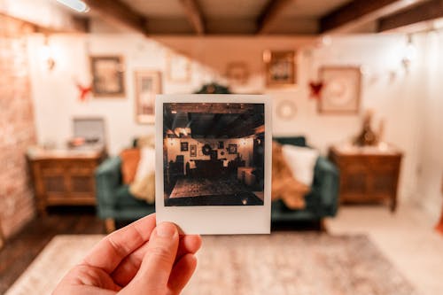 Hand Holding an Instant Photo of Living Room
