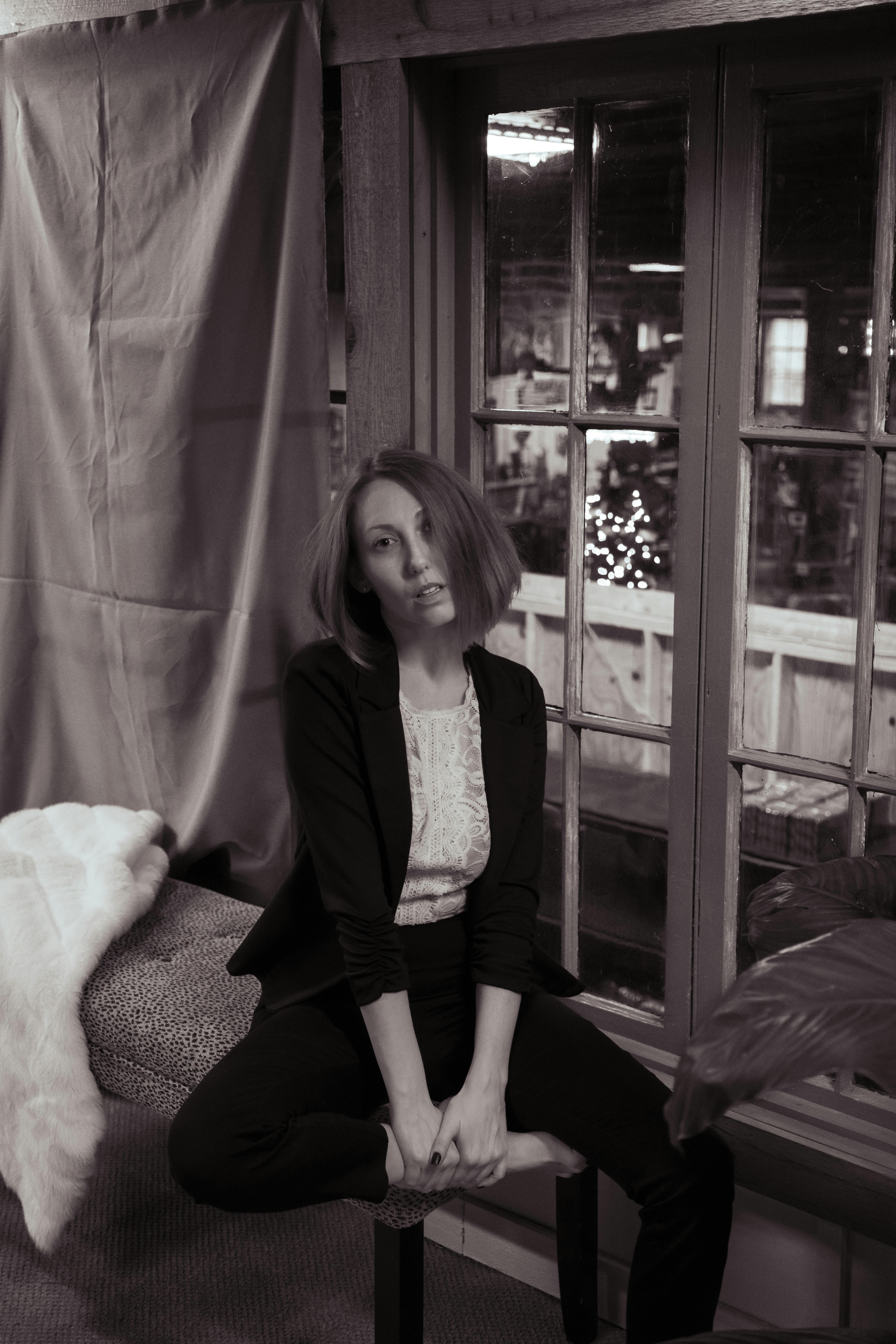 Sepia-toned portrait of a woman sitting indoors by a window, exuding modern style.