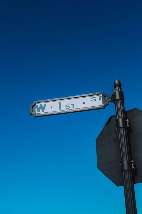 Free A street sign for W 1st St set against a vibrant clear blue sky. Stock Photo