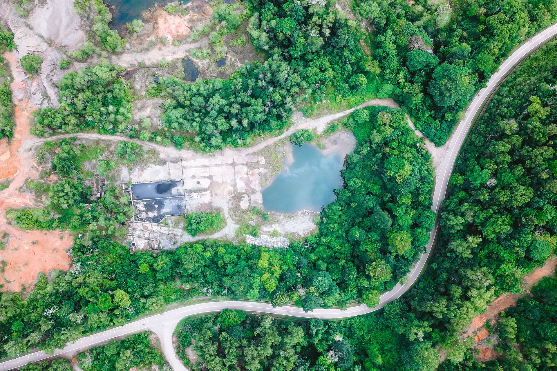 Vista aérea de un bosque frondoso alrededor de un sitio industrial y una laguna