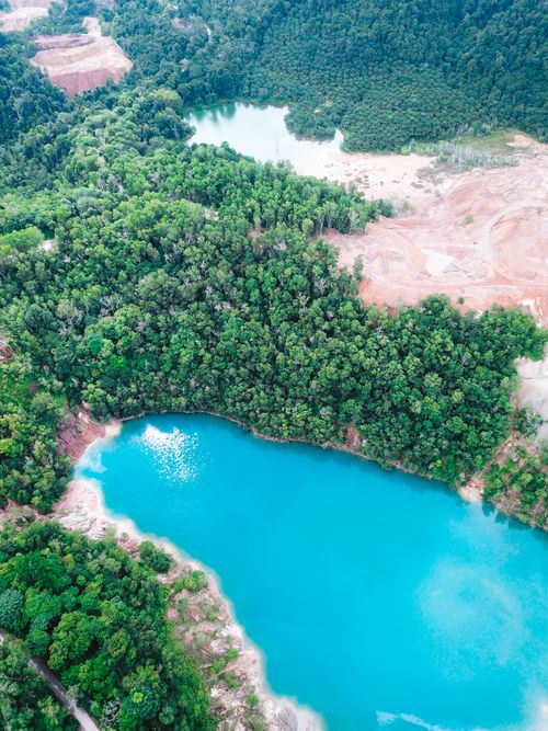Free Aerial shot of a vibrant blue lake amidst lush greenery in Muadzam Shah, Malaysia. Stock Photo