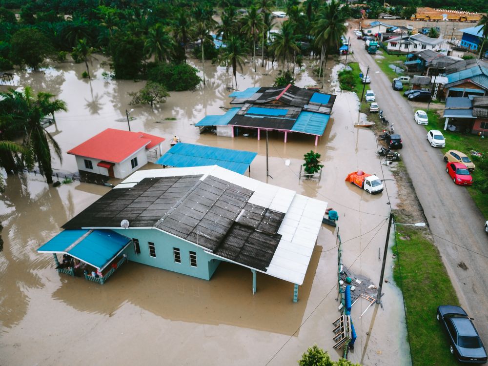 Aerial view of houses surrounded by floodwater in a Southeast Asian village
