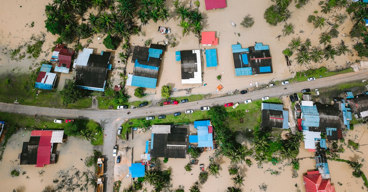 Luftaufnahme von überfluteten Wohnhäusern – ein Bild, das die konkreten Folgen des Klimawandels für Immobilien zeigt.