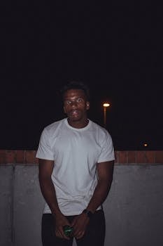 一位年轻人在夜间户外路灯下穿着白衬衫摆姿势的肖像