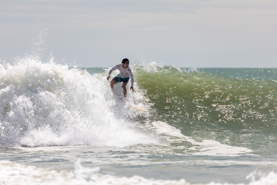 A man skillfully surfing a large wave under clear skies, perfect for summer adventures.