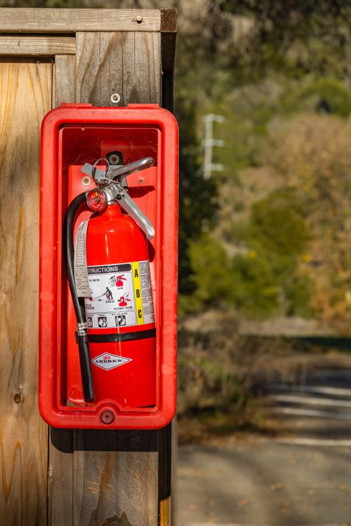 A Fire Extinguisher Mounted on a Wooden Post · Free Stock Photo