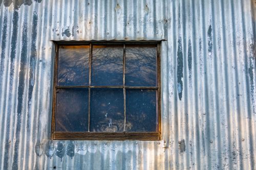 Free Rustic window set in a weathered metal facade reflecting an abstract landscape. Stock Photo
