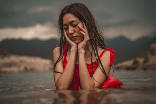 Serene moment of a woman in a red dress with a moody mountain backdrop.