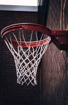 Close-up of a basketball hoop against a brick wall, highlighting the net and hoop detail.