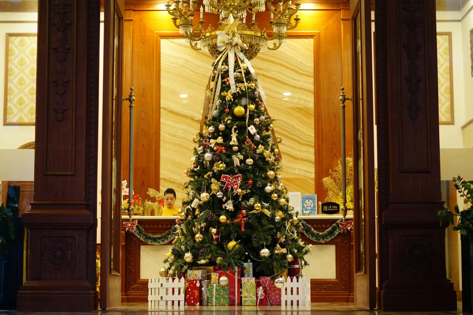 Elegant hotel lobby decorated with illuminated Christmas tree and wrapped presents.